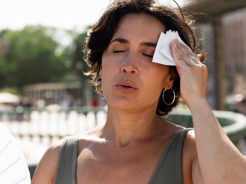 Mulher desconfotável ao se expor ao sol extremo, dentre vários problemas o sol envelhece a pele se não tiver cuidados adequados